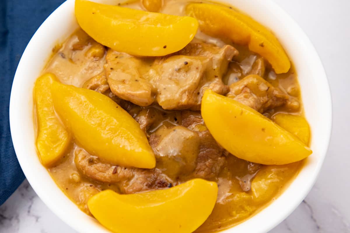 creamy peaches and pork on white bowl